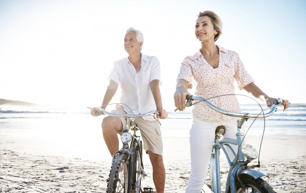 A couple enjoying anti-aging activities like riding bikes on the beach