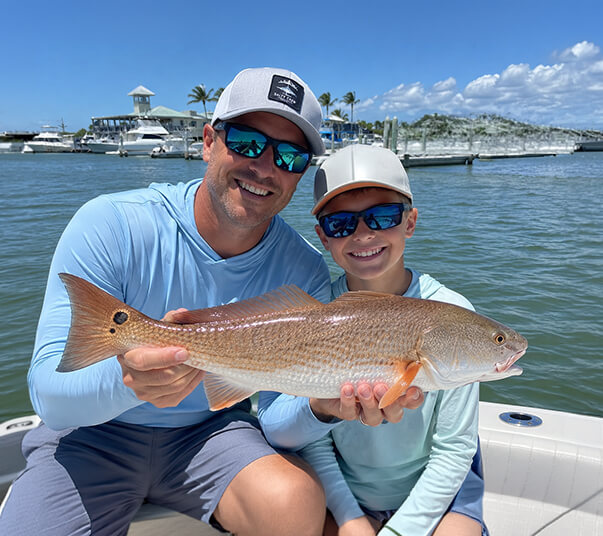 dad-and-son-holding-a-redfish-at-port-sanibel-marina