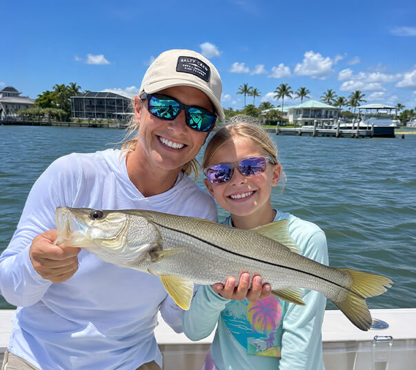 mom-and-daughter-holding-a-snook-at-port-sanibel-marina